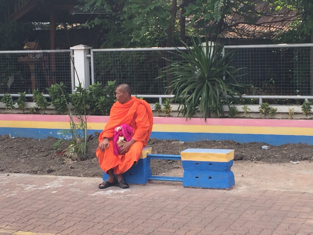 Un moine bouddhiste qui attend le train sur le quai. Les gares de Thaïlande sont magnifiques, fleuries, arborées